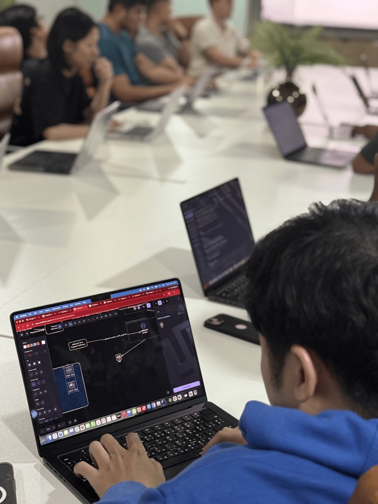 A developer sketching a payment-service architecture diagram on a laptop during a team session