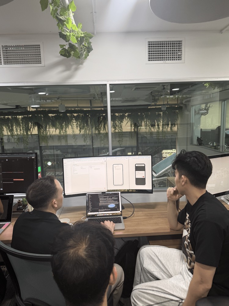 Teammates reviewing app screens together on a wide monitor